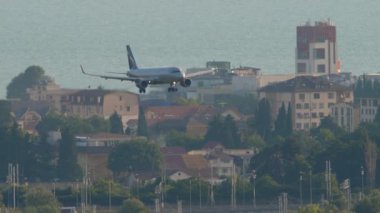 SOCHI, RUSSIA - 29 Temmuz 2022 Aeroflot yolcu uçağı Adler Havaalanı, Sochi 'ye inmek üzere iniyor. Şehrin arka planı ve otoyol. Turizm ve seyahat kavramı