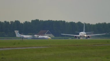 AMSTERDAM, NETHERLANDS - 24 Temmuz 2017: Yolcu uçağı Boeing 737, SAS Airlines 'dan LN-TUA, Schiphol Havaalanı' ndan kalkış. Arka planda Flybe turbo pervanesi var. Seyahat kavramı