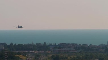 Gün doğarken bir şehrin üzerinde uçan ticari uçağın silueti. Şehrin üzerinde uçan bir uçağın güzel bir görüntüsü.