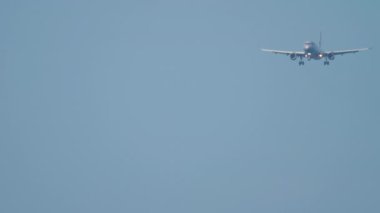 Footage of a jet passenger airliner approaching to land in the blue sky, long shot