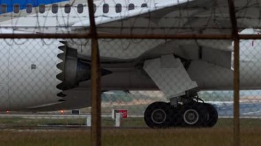 PHUKET, THAILAND - 31 HAZİRAN 2023: İniş pistinde Dreamliner Boeing 787. Chassis ve motor, yakın plan. Havaalanı çitlerinin arkasındaki uçak. Dikenli tel