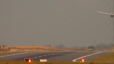 Sıcak bir günde pist görüntüsü. İniş yapmak üzere olan bir jet uçağı görüntüsü. Uçak iniyor, iniyor.