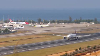 PHUKET, THAILAND - 23 Şubat 2023: uçağın aşırı saati. Emirlik 'ten Boeing 777' nin Phuket havaalanından kalkış görüntüleri. Geniş gövdeli uçak kalkışı. Turizm seyahati kavramı