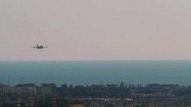 Ticari uçak jumbo jet silueti şehrin üzerinde uçuyor. Uçak şehrin üzerine iniyor. Uçak geliyor.