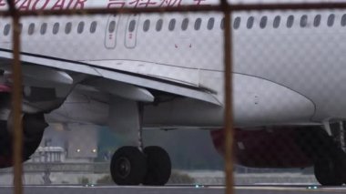 PHUKET, THAILAND - JANUARY 28, 2023: Airbus A320 of Juneyao Airlines taxiing at Phuket Airport. Chinese airline. Passenger plane on airfield, view through the fence. Tourism travel concept
