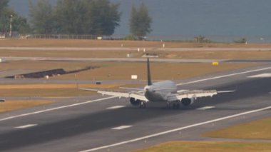 PHUKET, THAILAND - 13 Şubat 2023: Airplane Airbus A321 of Air Astana Phuket havaalanına indikten sonra fren yapıyor. Flaplar yukarı. Uçak geldi, havaalanı. Havaalanı, deniz kenarındaki havaalanı.