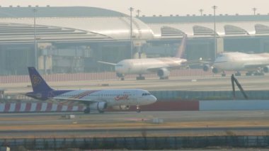 BANGKOK, THAILAND - 21 HAZİRAN 2023: Airbus A320, Thai Smile 'dan HS-TXF Suvarnabhumi Havaalanı' ndaki piste gidiyor. Havaalanı. Terminalde sıra sıra uçaklar, arka plan