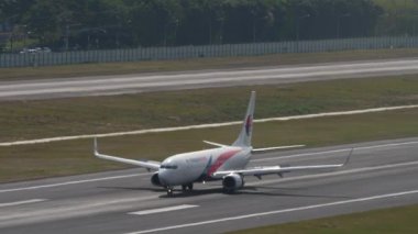 PHUKET, THAILAND - 11 Şubat 2023: Boeing 737, 9M-MXK Malezya Havayolları Phuket Havaalanı 'na indikten sonra fren yapıyor. Yolcu uçağı piste iniyor. Turizm ve seyahat kavramı