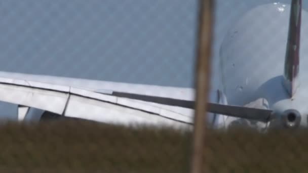 飛行機が着陸して滑走路に触れる低い角度の景色 翼の様子 エンジン ジェット機が到着する 旅客フライト 空港フェンス 航空機ブレーキのハンドヘルドシューティング トラベルコンセプト — ストック動画
