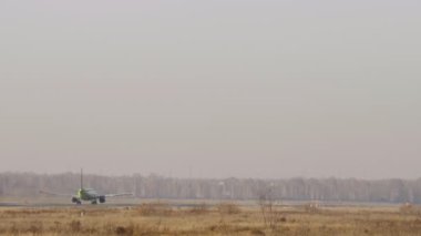 Tanınmayan üniformalı uçaklar uçup gidiyor. Pistteki bir uçağın uzun mesafeli görüntüsü. Uçuş kalkışı.