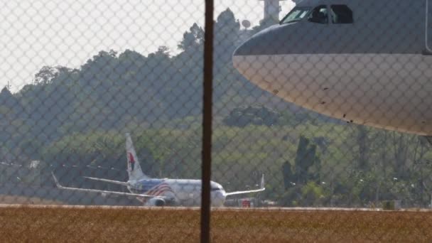 Phuket Thailand February 2023 プーケット空港でタクシーを運転するカタールの商用航空機 フェンスの上の飛行機 エアフィールド 観光と旅行のコンセプト — ストック動画
