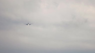 Passenger jet approaching before landing against a cloudy gray sky. Tourism and aviation concept