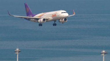 PHUKET, THAILAND - 20 Şubat 2023: Tay Gülüşü uçağı Phuket havaalanına iniyor. Uçak denizin üzerinde uçuyor. Turizm ve seyahat kavramı