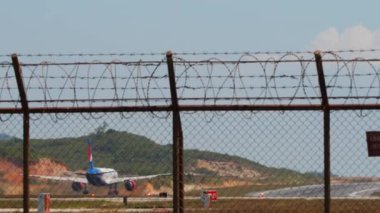 PHUKET, THAILAND - 10 Şubat 2023: Boeing 757, RA-73075 sayılı uçak Phuket Havaalanı 'ndan havalanıyor. Kalkış için uçak ivmesi. Uçak, çitin ötesine bak. Seyahat kavramı