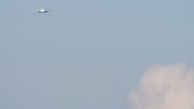 Jet yolcu uçağı güneşli bulutlu gökyüzüne inmek üzere yaklaşıyor. Gökyüzünde tanınmayan bir uçak var.