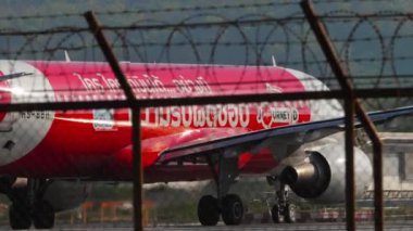 PHUKET, THAILAND - 10 Şubat 2023: Airbus A320, AirAsia Now Everybody can Fly Livery 'den Airbus A320, Phuket havaalanı, yan görüş pistine uçabilir. Havaalanı çitlerinin dışındaki uçak.