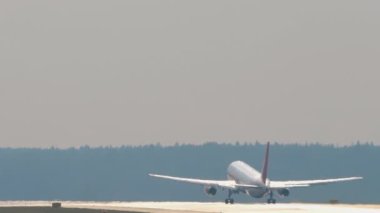 Bir jet uçağının arka planda havalanırken yavaş çekim görüntüleri. Uçak tırmanışı, dikiz manzarası