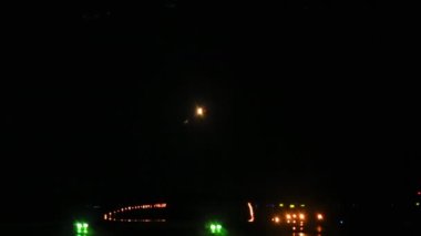 Gece inen bir uçağın görüntüsü. Pist iniş ışıklarıyla aydınlanıyor.