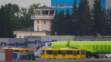 NOVOSIBIRSK, RUS FEDERASYONU - 10 Haziran 2020: Yolcular S7 Airlines uçağından inin. Uçak yolcularını bekleyen iki önlük otobüsü.