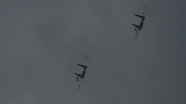 Gri bulutlu gökyüzünde askeri uçaklar. Savaş uçakları yüksekten uçuyor. Bir hava gösterisinde askeri teçhizat akrobasisi. Sıkıyönetim, havacılık kavramı
