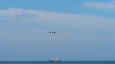 İnişten önce yolcu jet uçağı yaklaşıyor. Uçak mavi denizin üzerinde uçar. Arka planda yat, gemi veya balıkçı teknesi var. Havacılık kavramı