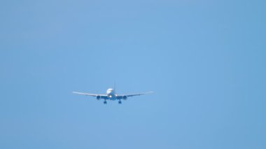 Front view of jet passenger jet plane in the blue sky. Airliner approaching for landing. Unrecognizable plane flies, arriving. Tourism and travel concept