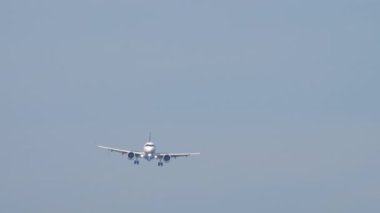 Tanımlanamayan bir üniforması olan yolcu uçağı iniş yapmak üzere, uzak ihtimal. Gökyüzünde bir jet uçağı, ön manzara.
