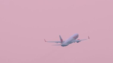 PHUKET, THAILAND - 27 Şubat 2023: Pembe günbatımında havalandıktan sonra Tayland Aslanı 'nın jet yolcu uçağı. Ticari uçak kalkışı. Uç bakalım. Seyahat kavramı