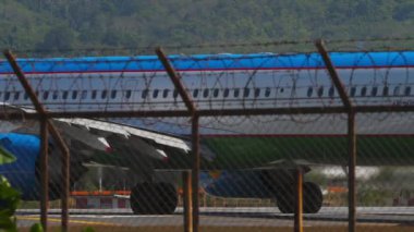 PHUKET, THAILAND - 10 Şubat 2023: Airbus A321, UK32103 Özbekistan Havayolları Phuket Havaalanı 'ndaki pistte taksicilik yapıyor, çitin arkasından dikiz görüntüsü