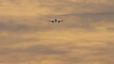 Jet uçağı inişe geçiyor, gün batımında gökyüzüne iniyor. Gökyüzünde uçan bir uçağın ön görüntüsü. Turizm ve seyahat konsepti. Uçak geliyor.