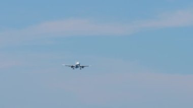 Mavi gökyüzüne iniş yapan bir jet uçağı, aşağıdan görünüyor. Yolcu uçağı geldi.