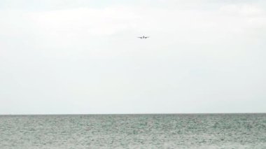 Jet uçağı inişe geçiyor. Okyanus üzerinde yolcu uçağı, bulutlu gökyüzü, ön manzara. Seyahat kavramı