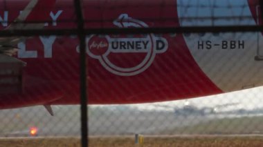 PHUKET, THAILAND - 10 Şubat 2023: Aircraft Airbus A320 with Now Everybody can Fly Livery 'nin Phuket havaalanındaki piste uçuşu. Havaalanı çitlerinin dışındaki uçak.