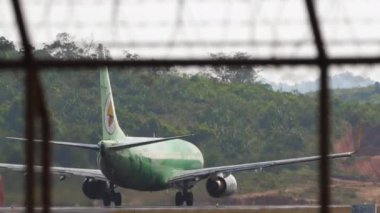 PHUKET, THAILAND - 19 Şubat 2023: Nok Air 'in Boeing 737' si Phuket havaalanında kalkış için hızlanıyor. Yolcu uçağı kalkıyor. Havaalanı çitlerinin arkasında Asya uçağı var. Havaalanı