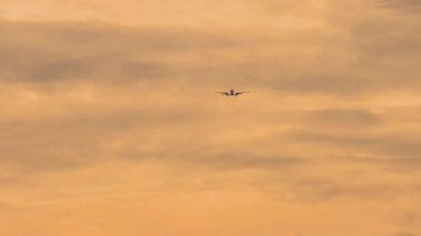 Güzel gün batımı ışığında bulutların üzerinde uçan ticari uçak. Seyahat konsepti. Düşük ihtimal, yolcu uçağı yaklaşıyor.