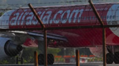 PHUKET, THAILAND - 10 Şubat 2023: AirAsia uçağı Phuket havaalanı, arka görüş pistinde taksicilik yapıyor. Yolcu uçağı kalkıyor. Turizm seyahati kavramı