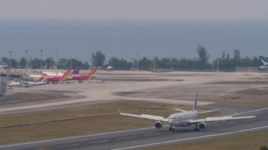 PHUKET, THAILAND - 13 Şubat 2023: Airbus of Qatar Airways Phuket havaalanına indikten sonra fren yapıyor. Denizin arka planı. Turizm ve seyahat kavramı