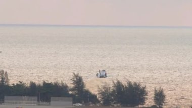 Uçak havalanıyor ve denizin üzerinde uçuyor. Tatil, havacılık, seyahat, gezi konsepti, fotokopi alanı. Ticari uçak kalkışı, okyanusa tırmanma, arka planda güzel bir günbatımı.