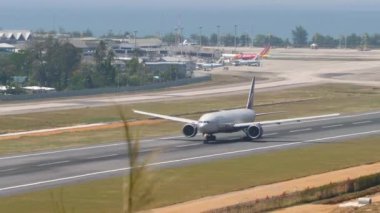 PHUKET, THAILAND - 23 Şubat 2023: Geniş gövdeli Boeing 777-300ER, Phuket havaalanından kalkan RA-73146. Yolcu uçağı kalkıyor, kalkıyor, yan görünüm