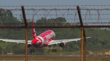PHUKET, THAILAND - 22 Şubat 2023: Airbus A320, AirAsia 'dan HS-BBI, Phuket havaalanında fren yapıyor. Çitin arkasındaki uçağın görüntüsü. Spoiler verin. Seyahat kavramı