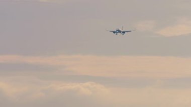 Jet yolcu uçağı inişe geçiyor. Gün batımı ya da şafak, gökyüzünde bir uçak. Uçak inişi, varış. Seyahat kavramı