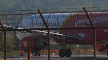 PHUKET, THAILAND - 10 Şubat 2023: Airbus A320-214, Vietnam Jet Air 'in HS-VKP' si Phuket havaalanı pistine taksicilik, orta atış, yan görüş, havaalanı çiti