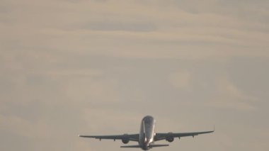 Büyük yolcu uçağı güzel gün batımına karşı kalkıyor. Yüksekliğe tırmanan bir uçağın uzun görüş açısı silueti