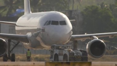 PHUKET, THAILAND - 19 Şubat 2023: Airbus A320, Phuket Havaalanı 'ndaki Tayland Jet HS-VKT. Arka planda güneş ışığı alan bir uçak. Traktör uçağı çekiyor. Turizm ve seyahat kavramı.