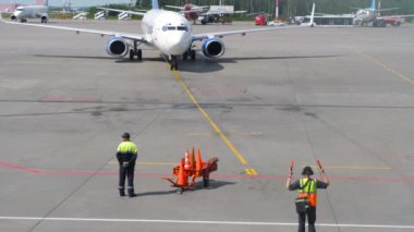 SAINT PETERSBURG, RUSSIA - 26 Temmuz 2022: Boeing 737-86N, RA-73261 Yakutia Airlines 'ın Pulkovo havaalanında taksicilik yapması, havaalanındaki havacılık marshaller işi