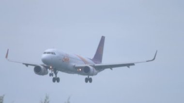 PHUKET, THAILAND - 28 Kasım 2019: Tayland Gülüşü uçağı Phuket Uluslararası Havaalanına iniyor, yan görüş. Uçak uçuyor. Gökyüzünde yolcu uçuşu