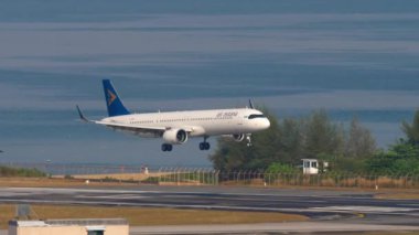PHUKET, THAILAND - 20 Şubat 2023: Phuket havaalanına inen Air Astana 'nın modern yolcu uçağı Airbus A321. Uçak mavi denizin üzerinde uçar. Seyahat kavramı