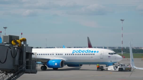 2022年7月26日 一架拖拉机将一架波贝达波音737客机拖到滑行道上 滑行在圣彼得堡普尔科沃机场跑道上 — 图库视频影像