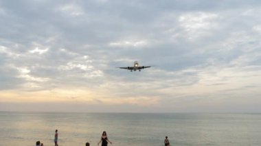 PHUKET, THAILAND - 26 HAZİRAN 2023: Pazar Havayolları Boeing 767 kalabalık bir sahil üzerinde uçuyor. Turistler uçan bir uçağın önünde fotoğraf çekerler. Millet, uçak geçmişi. Seyahat kavramı