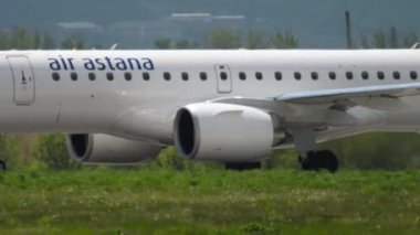 ALMATY, KAZAKHSTAN - 5 Mayıs 2019: Almaty havaalanından kalkan Air Astana 'nın ticari uçağı Embraer E190. Turizm ve seyahat konsepti. Uçak kalkış, yan görüş
